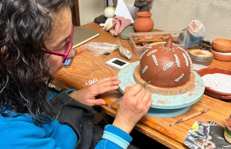 Oleira a trabalhar o barro com a colagem de pedras de quartzo para decoração